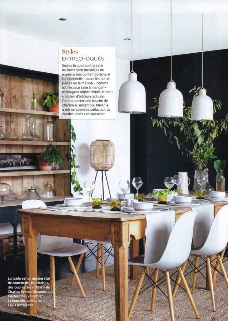 Salle à manger design : suspension blanche et table en bois, affiche « Styles ENTRECHOQUÉS ».